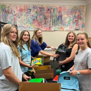 Children helping stuff backpacks